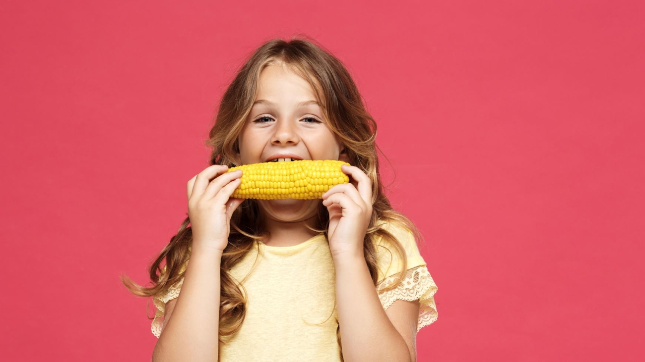 young-pretty-girl-eating-corn-pink-wall2-min
