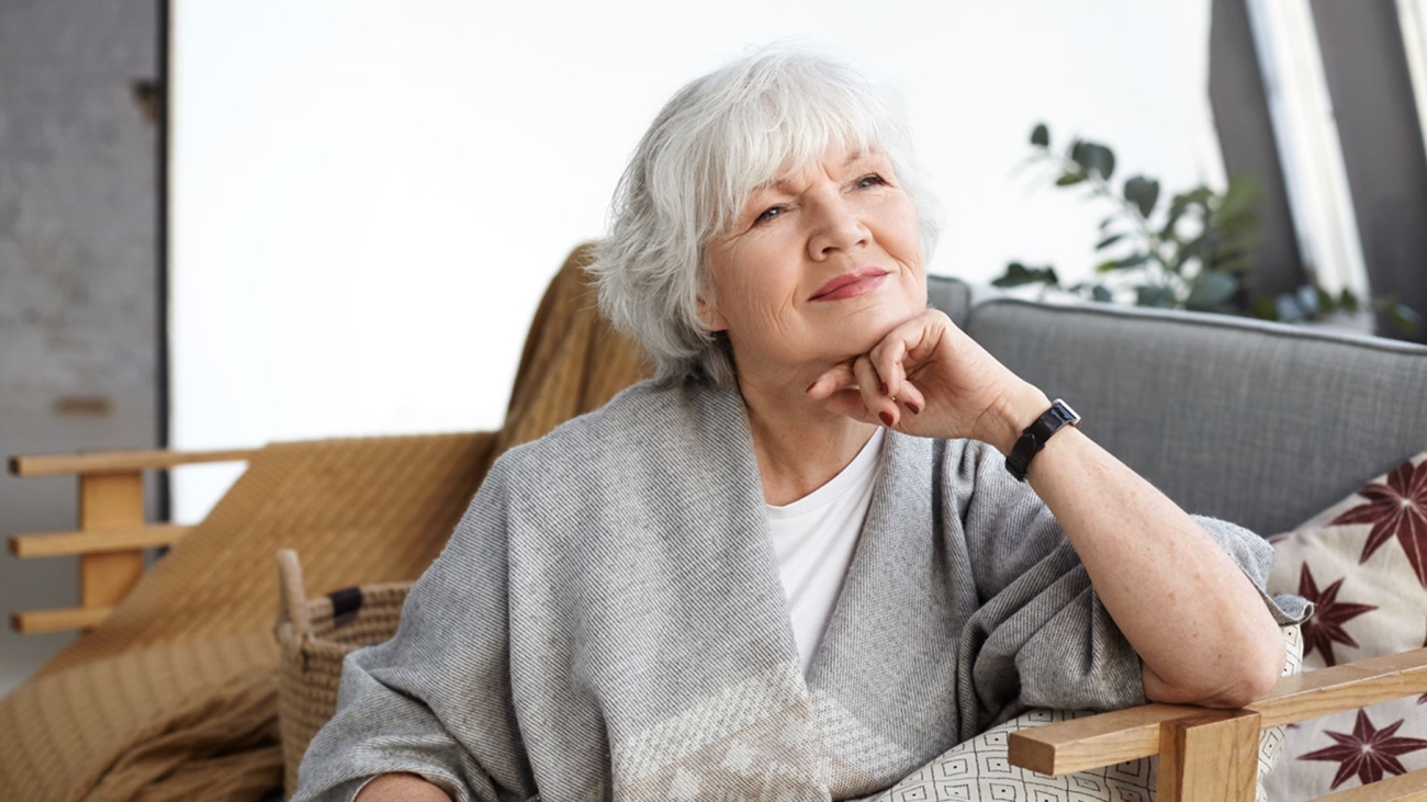 portrait-lovely-middle-aged-grey-haired-european-woman-with-dreamy-smile-eyes-full-wisdom-relaxing-home-alone-sitting-comfortable-couch-reminiscing-about-days-her-youth3-min