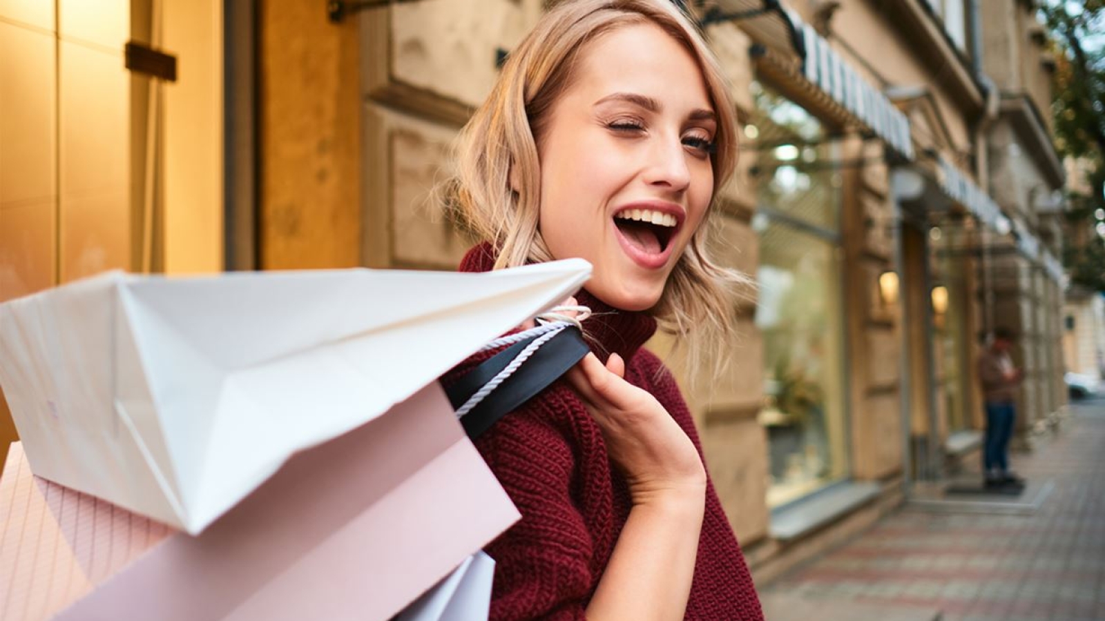 portrait-cheerful-blond-girl-with-shopping-bags-happily-winking-out-city-street2-min
